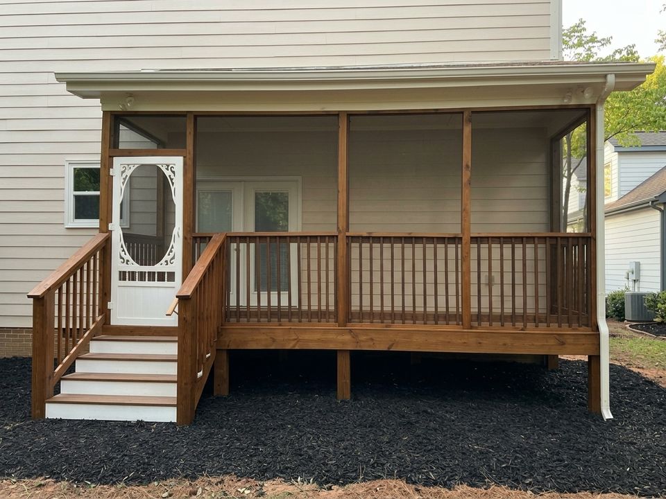 New screened porch with stained wood railings, white screen door and steps, set in fresh black mulch